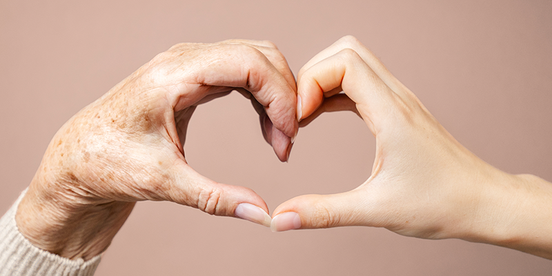Hand heart old and young on a beige pink background